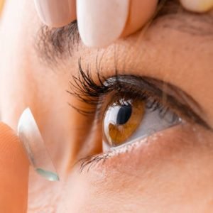 Close up woman applying contact eye lens