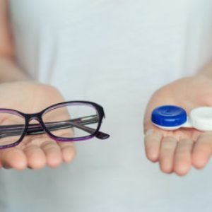 woman hold contact lenses and glasses in hands close up. concept of choice of vision protection